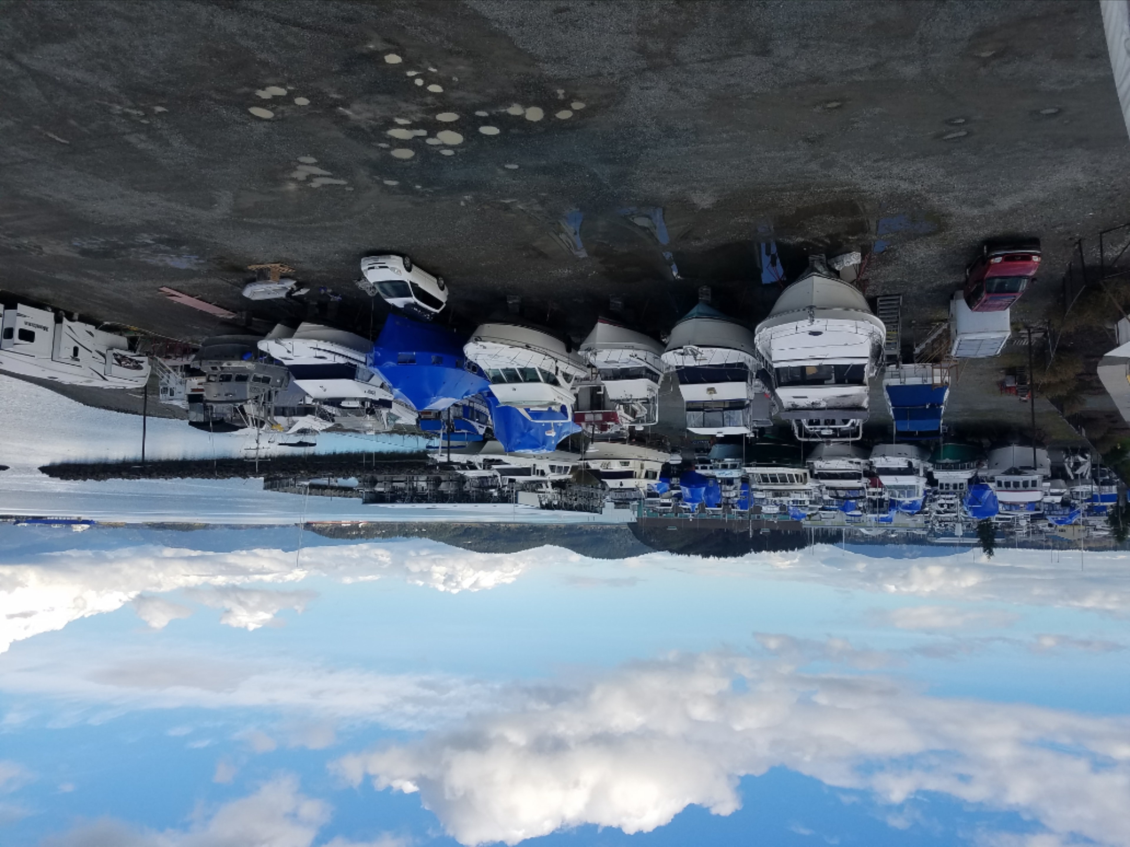 NHD boatyard dry storage yard filled with motor yachts and cruisers on stands under a blue sky with Cascade Mountains in the background