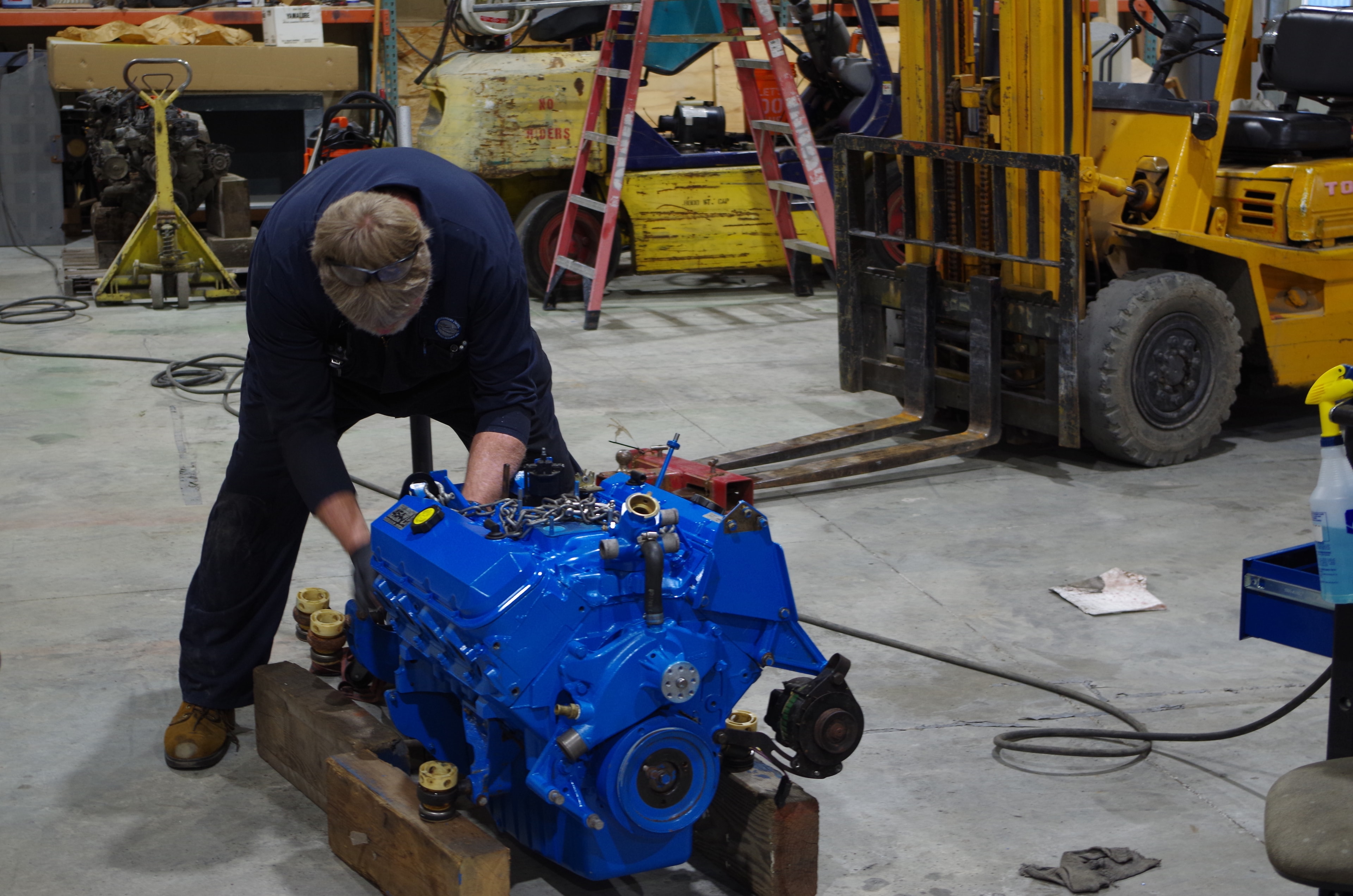 Technician rebuilding a freshly painted blue marine diesel engine on the shop floor