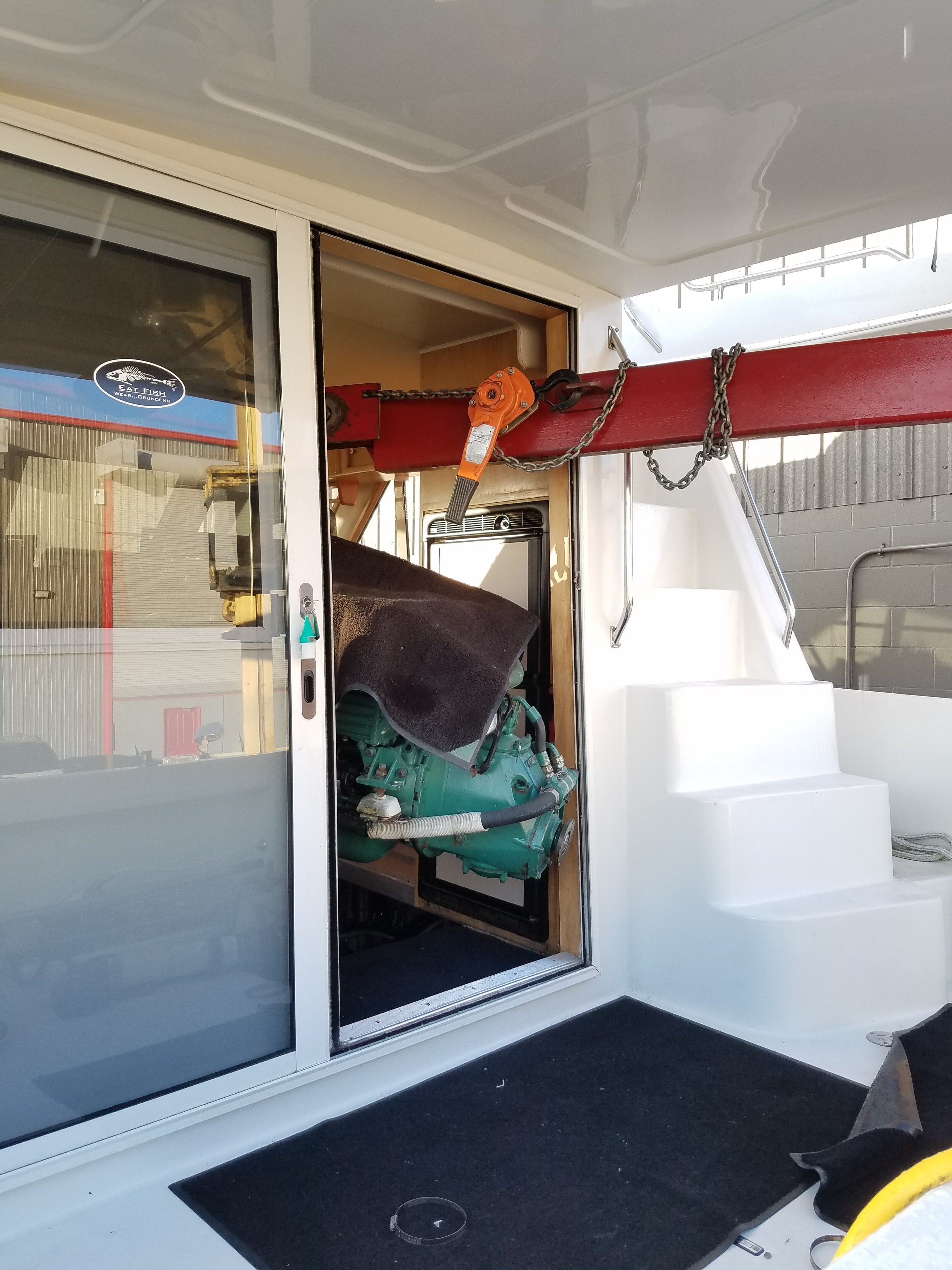 Volvo Penta engine being hoisted into boat engine compartment with chain hoist