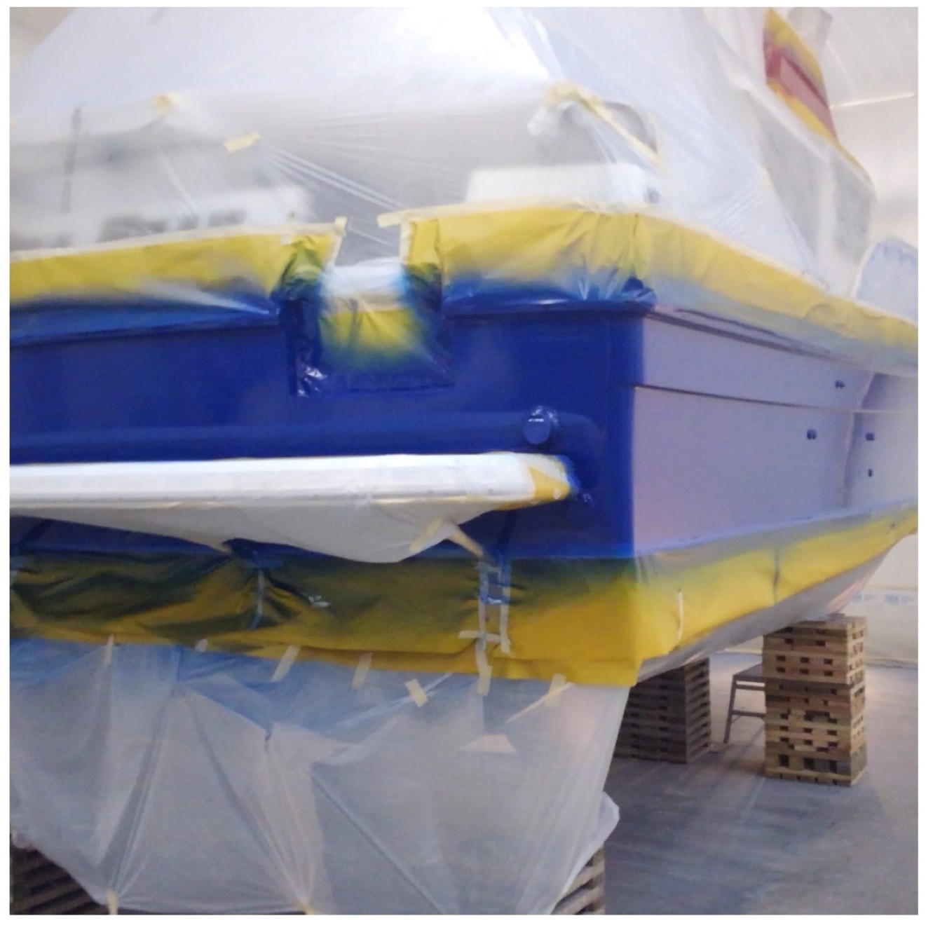Sea Bear catamaran with bold cobalt blue hull paint in progress inside NHD paint booth